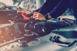 mechanic using multimeter on car engine battery