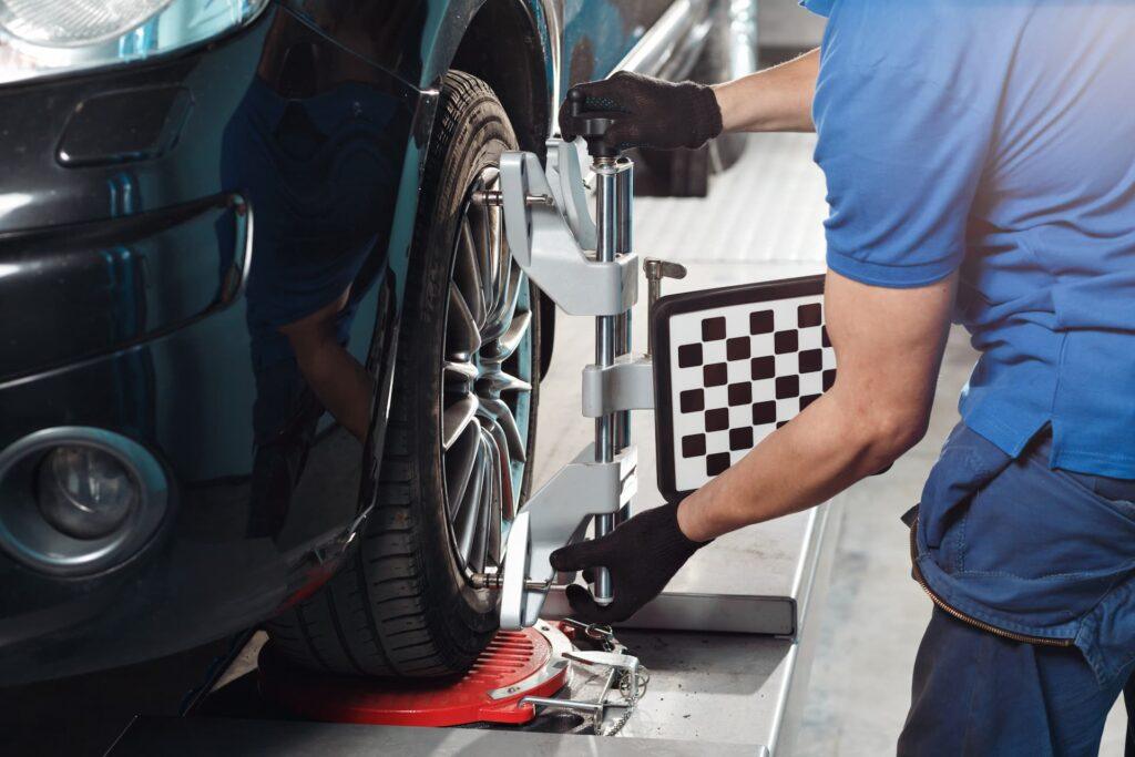 mechanic preforming wheel alignment on a car