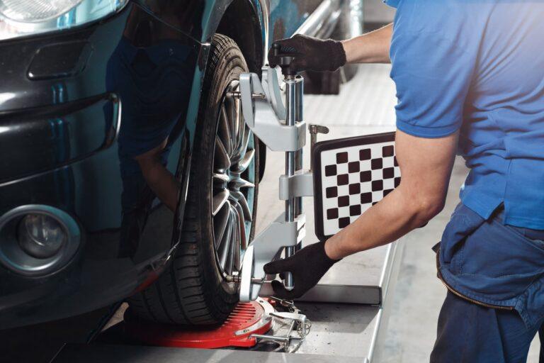 mechanic preforming wheel alignment on a car